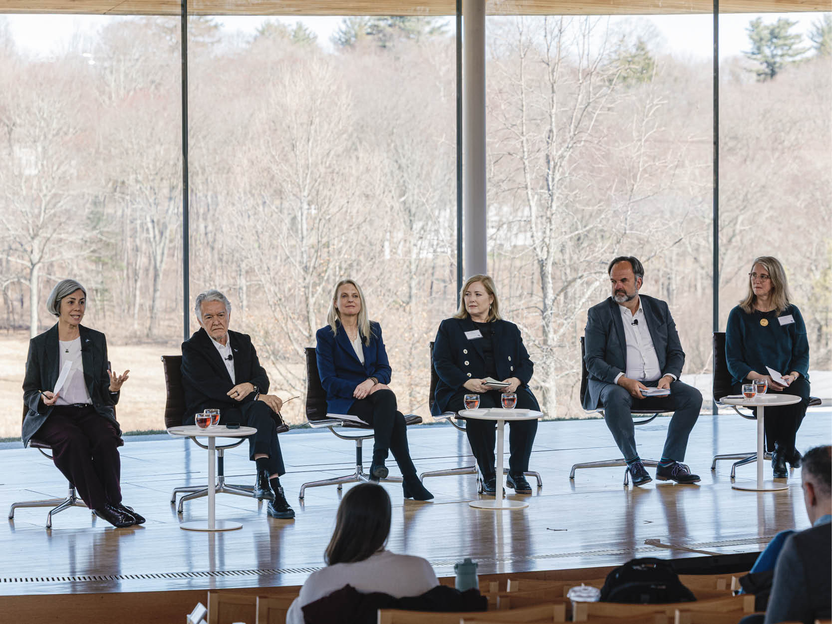 Photograph of a panel of 6 speakers onstage