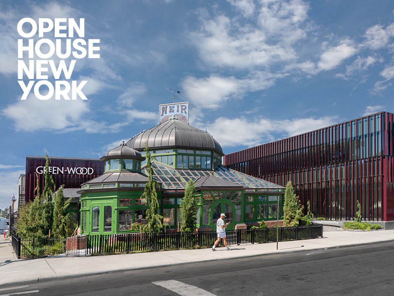 Man walks on the sidewalk in front of a greenhouse