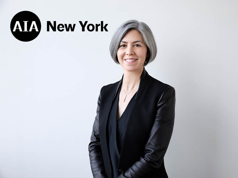 Woman wearing black standing against a white wall