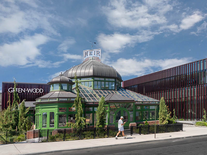 Man walking in front of a historic greenhouse structure.