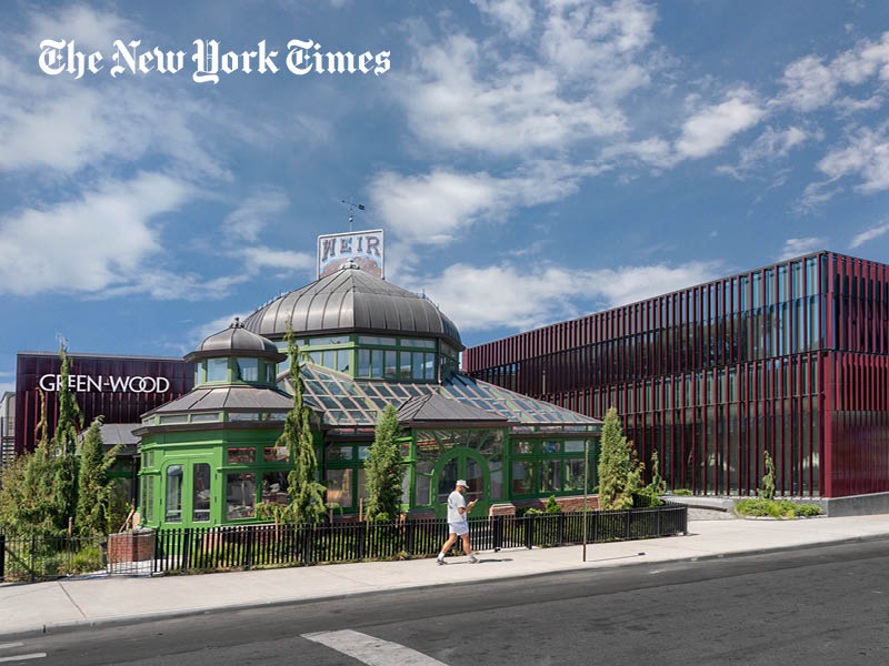 Man walks in front of a Victorian greenhouse and new welcome center
